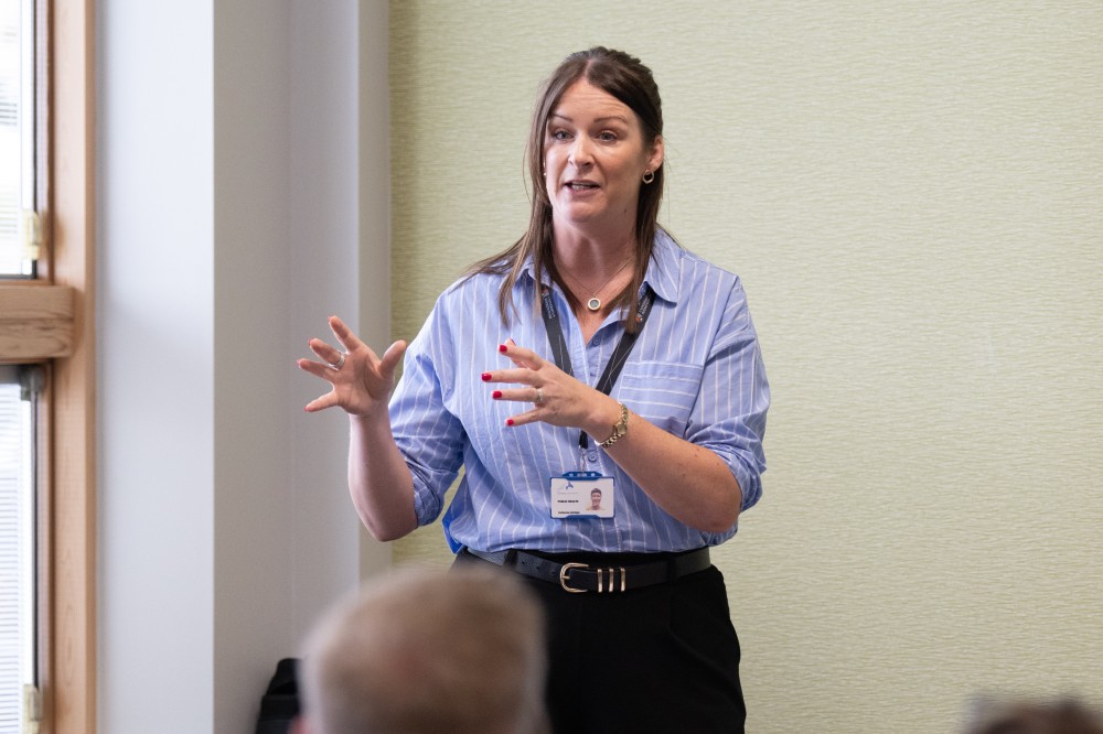 A person stood at the front of a wellbeing forum giving a talk