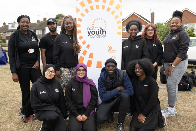 Group of young people stood by a Positive Youth sign