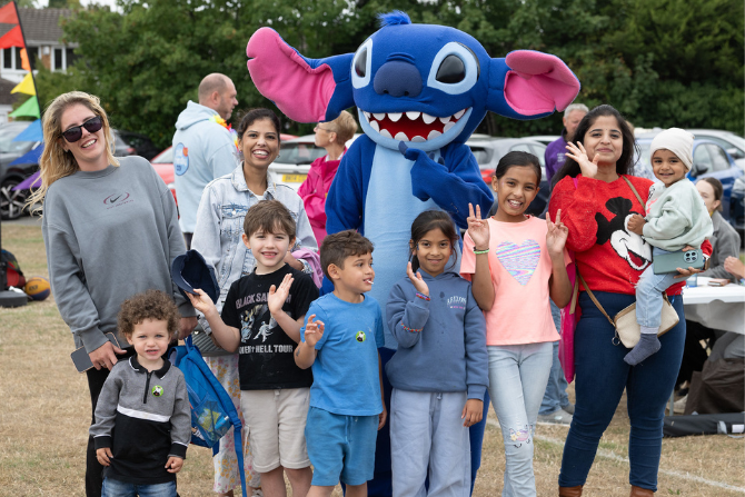 Group of people stood in front on someone dressed in a Stitch costume