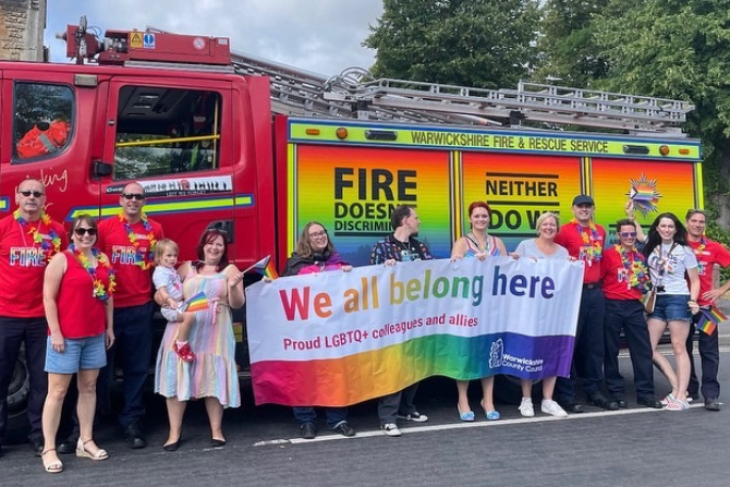 Group of people stood in front of a fire engine and celebrating LGBTQ