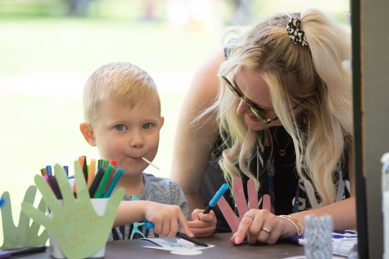 woman and child, with a lollypop, at a crafts table.